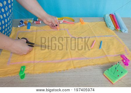 Close up of woman's hand Makes out a pattern from a yellow piece of clothes. Concept of self made clothes