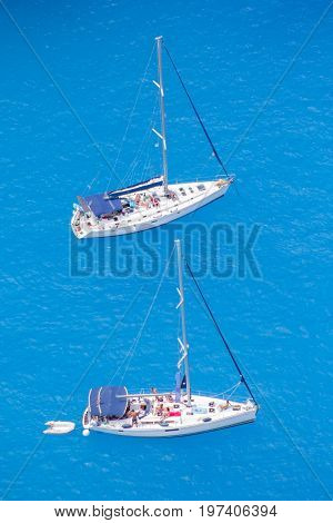 View from the top of the Mediterranean Sea and two white sailboats with people on the deck