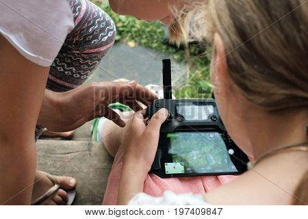 Two girls playing with drone gps tracking while holding a drone remote control cropped closeup