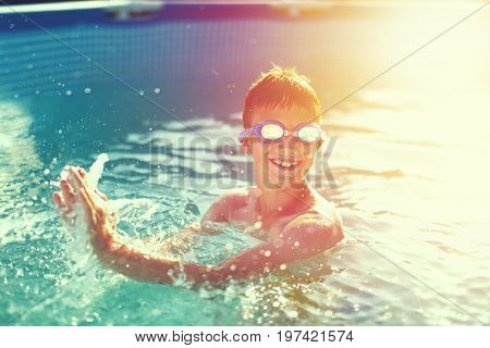 Happy kid with teeth smile splasing in swimming pool enjoying summer holiday vintage style