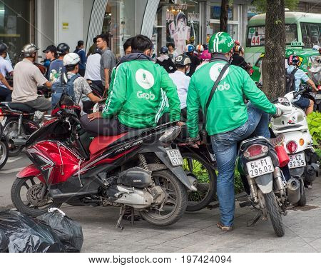 Ho Chi Minh City Vietnam - July 28 2017: Motorbike taxi driver from the controversial Grab ride-sharing system in downtown Ho Chi Minh City. Grab and the similar Uber have been accused of pressing prices and thereby redusing earnings for the drivers.