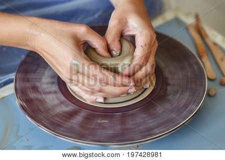 Creating a jar or vase of clay. Woman hands on potter's wheel