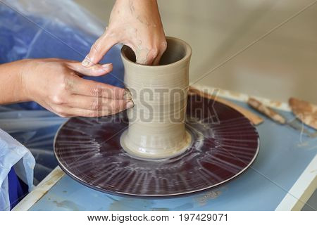 Creating a jar or vase of clay. Woman hands on potter's wheel