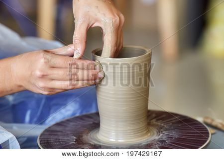 Creating a jar or vase of clay. Woman hands on potter's wheel