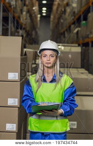 Female warehouse worker looking at camera in logistic center