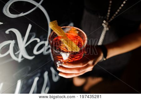 Negroni in the hand on a black background. Close up
