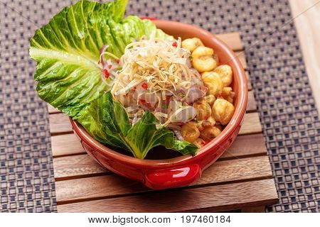 Fresh salad with lupini beans and raw fish served with lettuce leaf in bowl on table napkin
