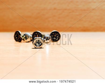 View of the cruciform slot of the screw through the nut. The fixing tools lie on a light wooden surface