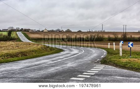 Image of an empty winding road in a countryside region of France in a bad weather day.
