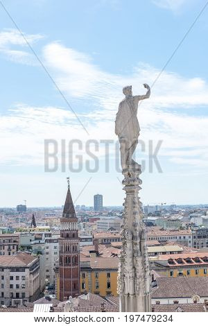 Gothic spire on the roof of Milan Duomo with aerial view of Milan Italy.