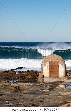Newcastle Ausralia - Large surf breaking beyond the pumphouse at the Cowrie Hole - Newcastle Australia. This pumphouse is a local landmark and delivers water to the adjacent Newcastle ocean baths.