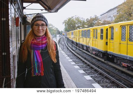 Young hipster woman in glasses and in warmclothes in train station platform, portrait