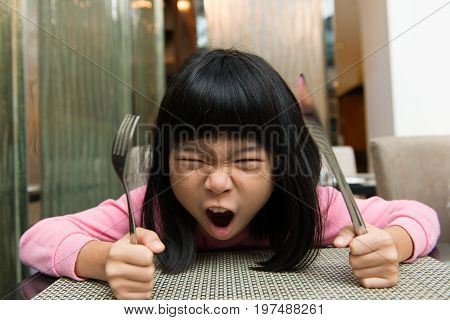 Little Asian girl waiting at table screaming for food