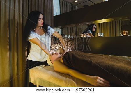 Woman having face massage treatment in wellness center.