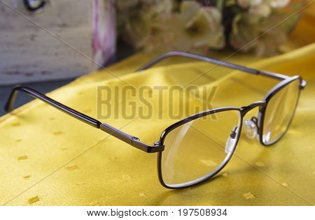 Closeup of diopter glasses on the table with flowers and old box