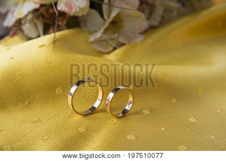 Closeup of wedding rings on the yellow tablecloth background