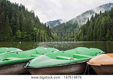 Mountain lake scenery Lacu Rosu or Red lake with boats near the shore Eastern Carpathians Romania nature landscape background.