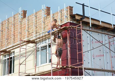 KYIV UKRAINE - AUGUST 16, 2017: Construction workers insulating house facade with mineral rock wool and siding installation. External wall insulation system (or EWIS) mineral wool for energy saving.