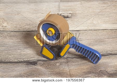 Industrial tape dispenser on a wooden background