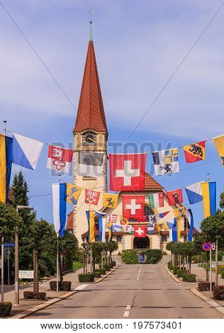 Wallisellen, Switzerland - 30 July, 2017: Kirchstrasse street decorated with flags for the upcoming Swiss National Day, the protestant church in the background. Wallisellen is a town in the Swiss canton of Zurich.