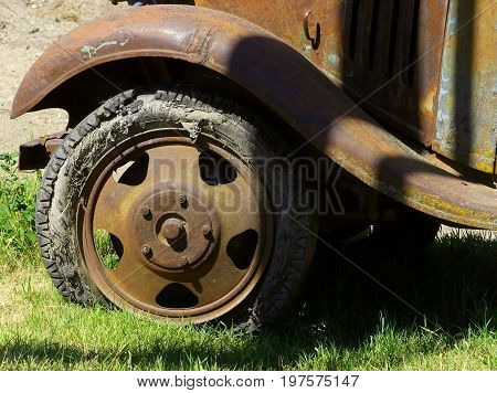 The front fender and wheel off of a vintage truck in need of a new tire.