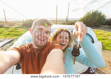 Young funny couple with keys to new car outdoor.