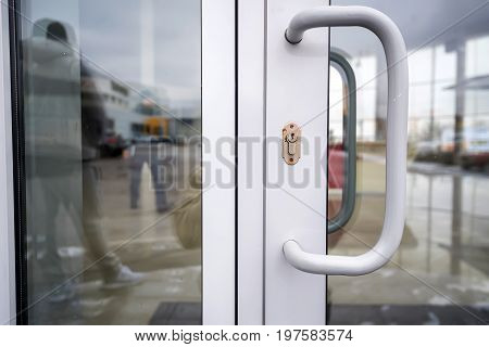 Close-up of chrome doorhandle and glass office doors with keyhole