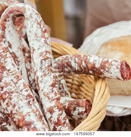 Close-up of traditional italian tasty delicacies in wicker basket, picant organic salami in market. Gastronomic products for gourmets