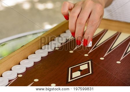 Backgammon Bone Square White Dice For Gambling With Blurred Background. Woman With Red Nails Is Play