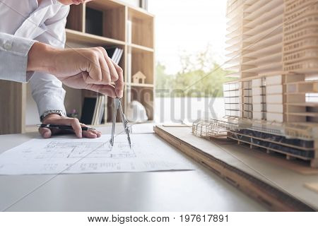 Engineering or Creative architect in construction project Engineers hands working with compasses on construction blueprint building at a workplace in office Building and architecture concept.