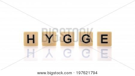 HYGGE spelt on word tiles on a white background Hygge is a Danish and Norwegian word which can be described as a quality of cosiness and comfortable conviviality that engenders a feeling of contentment or well-being.