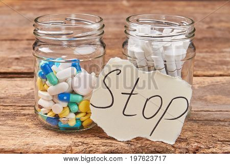 Cigarettes and pills, wooden background. Jars with pills and cigarettes. Stop nicotine addiction concept.