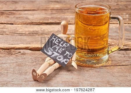 Help to stop alcohol addiction. Human wooden dummy, message, rustic glass of beer, old wooden background.