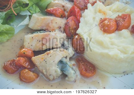 Sliced chicken with mashed potato and tomato cherry in italian sauce. Italian restaurant. delicious dinner.
