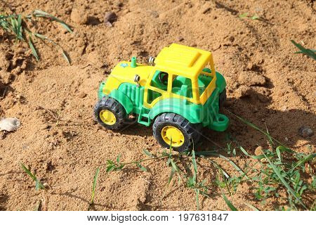 Greenand yellow tractor toy on the sand