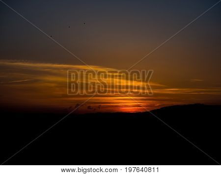 Sunset on the Spanish coast with silhouetted earth and predominance of orange color
