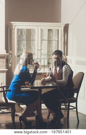 Girl and hipster dating in restaurant. Woman with blond hair and man drinking wine from martini glasses. Couple in love. Alcohol and appetizer. Addictive and convive. Unhealthy lifestyle. Bad habits