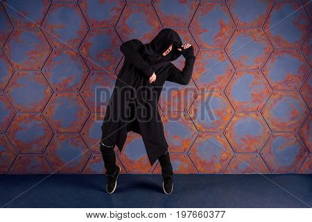 Young dancer standing on his tiptoes near the wall. Urban style