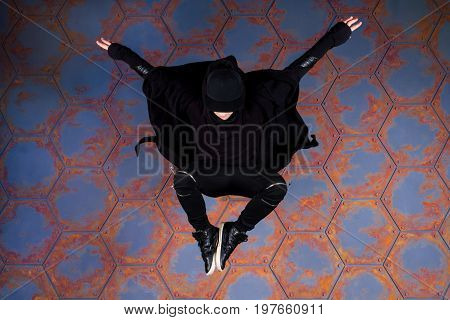 Young dancer jumping high near the urban wall.