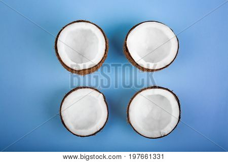 Four cut tropical and exotic coconuts on a light blue background. Nutritious exotic nuts. Tasty and bright brown nuts. Cut and sweet cocos. Fresh, ripe and organic fruit of coconuts.
