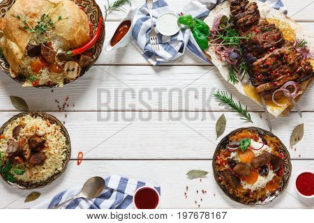 Variety of georgian cuisine dishes with meat on wood table. Shah pilaff, kebab and different types of rice with meat on free space background