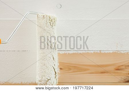 Roller paints white paint a fresh wooden floor