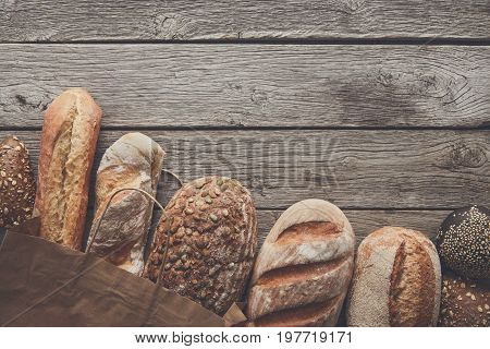 Bread border on rustic wood with copy space background. Brown and white whole grain loaves still life composition with wheat flour sprinkled around.