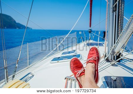 A pair of man legs in red topsiders on white yacht deck. Yachting