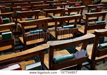 Stratford-upon-avon, UK - July 21 2017: Rows of wooden empty chairs in a church with bibles and prayer books