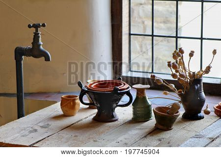Old Fashioned Brass Standpipe Water Tap Or Fawcett, Over A Wooden Bench With Antique Tudor Style Pot