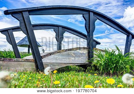 Small Bridge By Yellow Dandelion Flowers By Saint Lawrence River In La Malbaie, Quebec, Canada In Ch