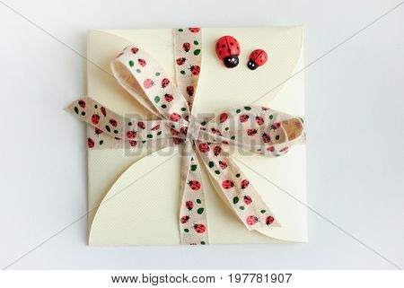 Gift envelope with bow and ladybugs on white background