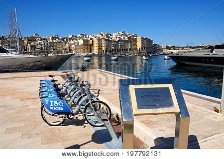 VITTORIOSA, MALTA - MARCH 31, 2017 - Plaque for the Maltese Prime Minister Lawrence Gonzi along the waterfront with hire cycles to the rear and views of the harbour and Senglea Vittoriosa (Birgu) Malta Europe, March 31, 2017.