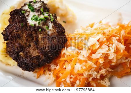 Minced beef cutlet with mashed potatoes in creamy sauce and carrot-cabbage salad